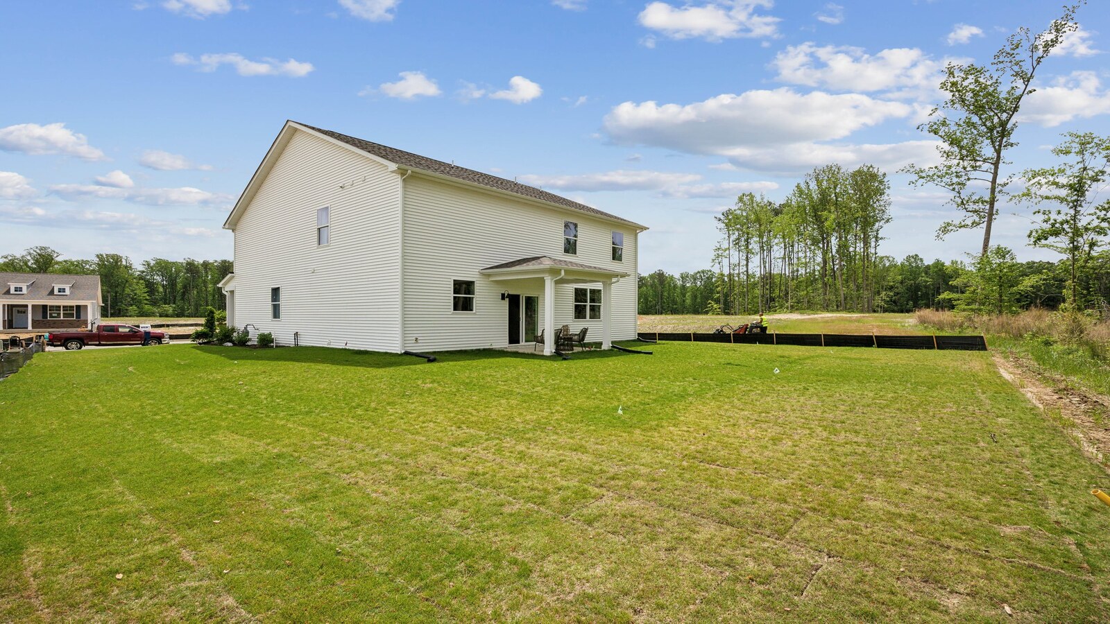 New Build Home by D.R. Horton featuring a spacious backyard with grass lawn and a covered rear patio area
