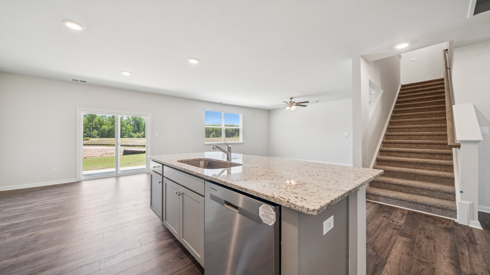 Wide view from living room showing kitchen island, pantry entry, and stair design at Smith Farm