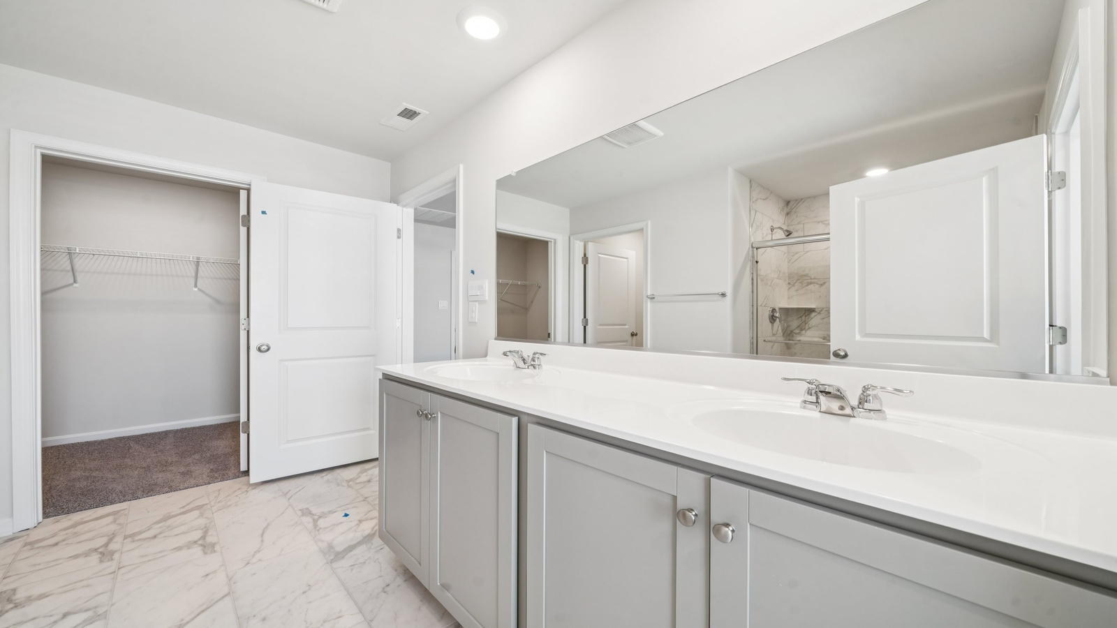 Primary bathroom in this New Build Home includes extended vanity, quality cabinets, walk-in closet and spa-inspired design
