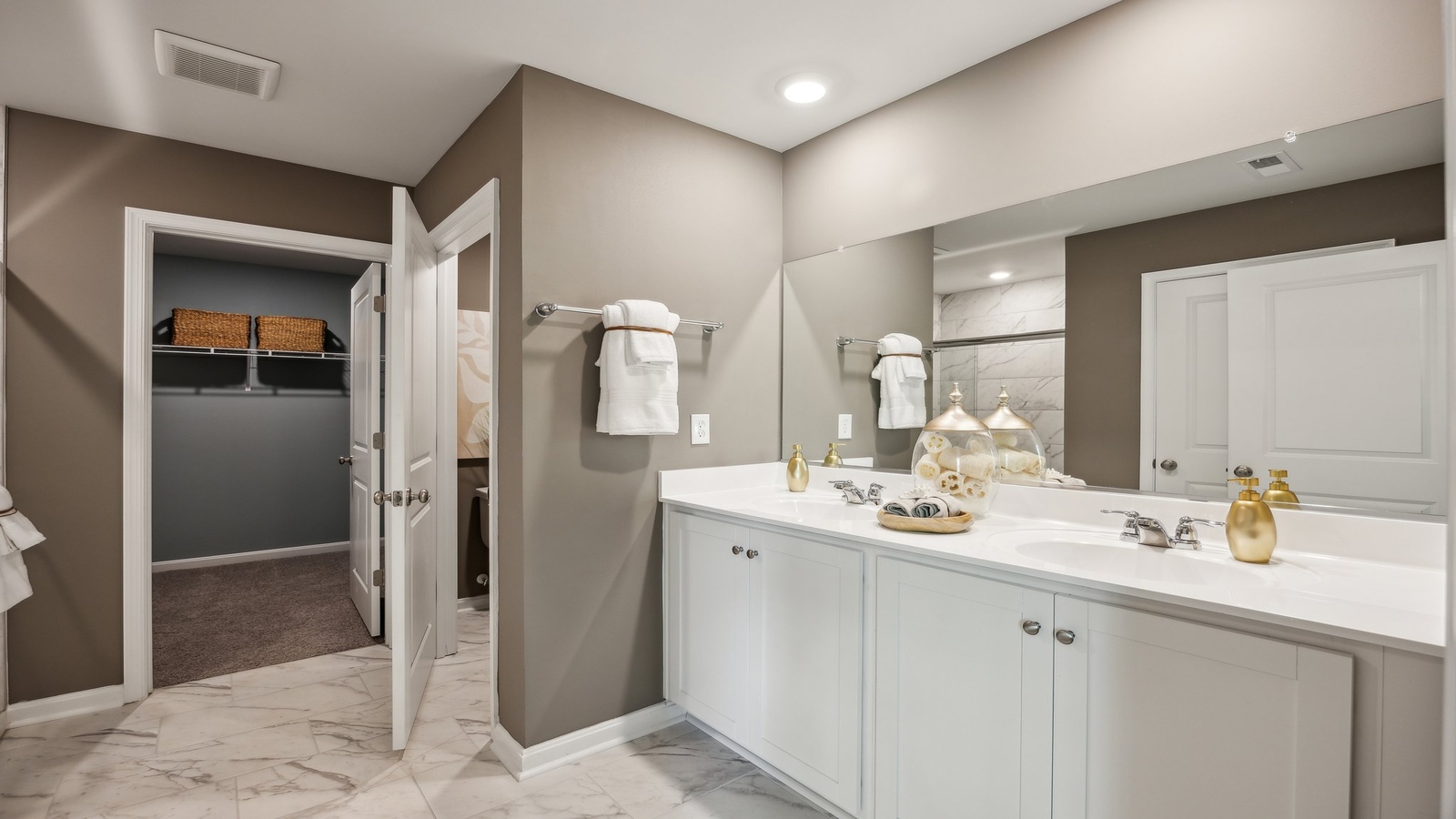 Primary ensuite bathroom in this D.R. Horton new home featuring expansive vanity with dual sinks, shower-tub, walk-in closet