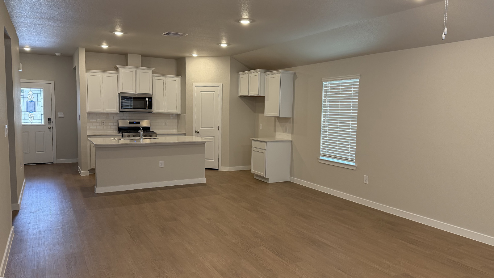 Living room looking to dining and kitchen areas in this new home features natural light, with fresh open concept flow