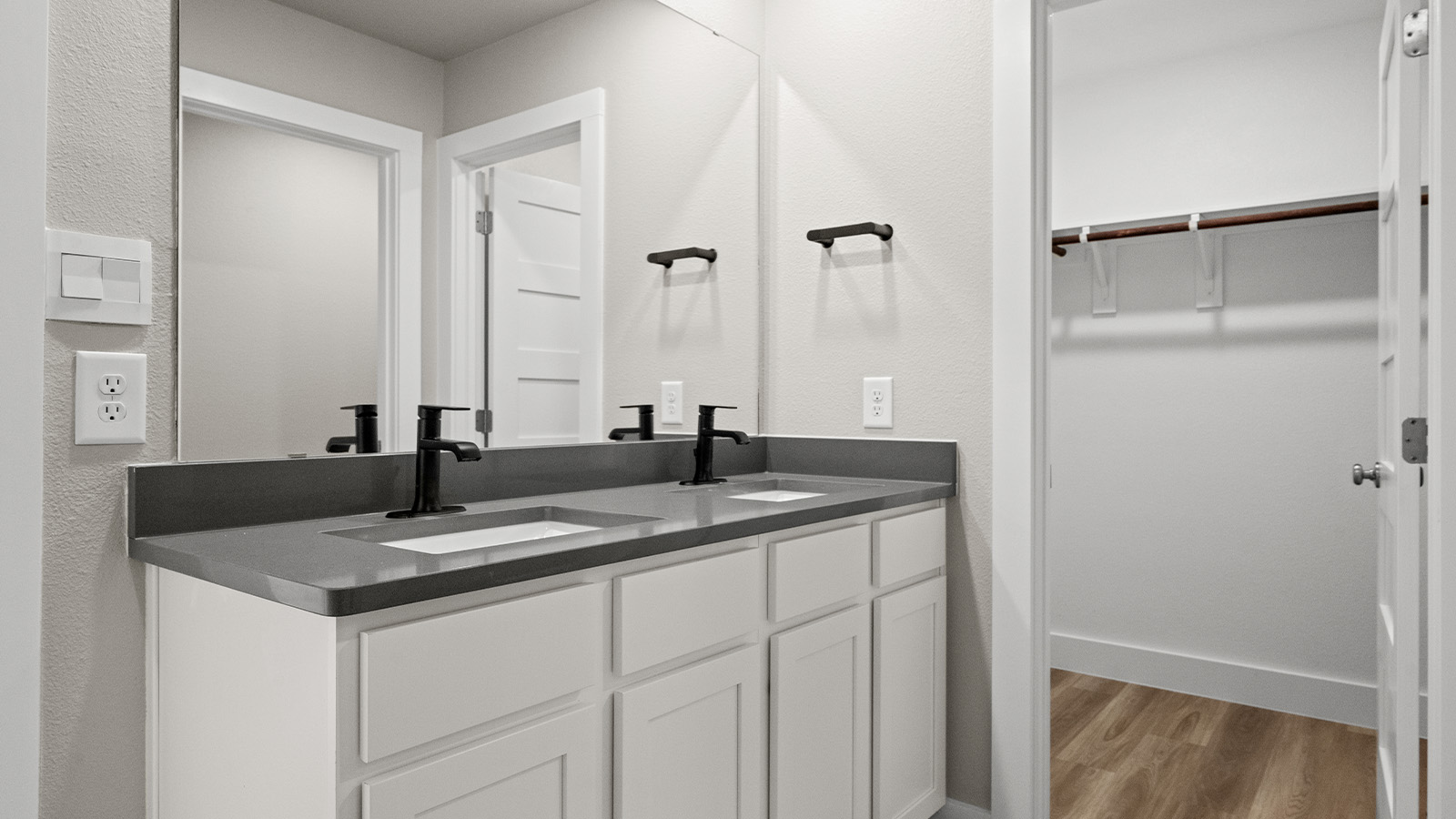 Primary bath with white shaker cabinets and dark quartz counters