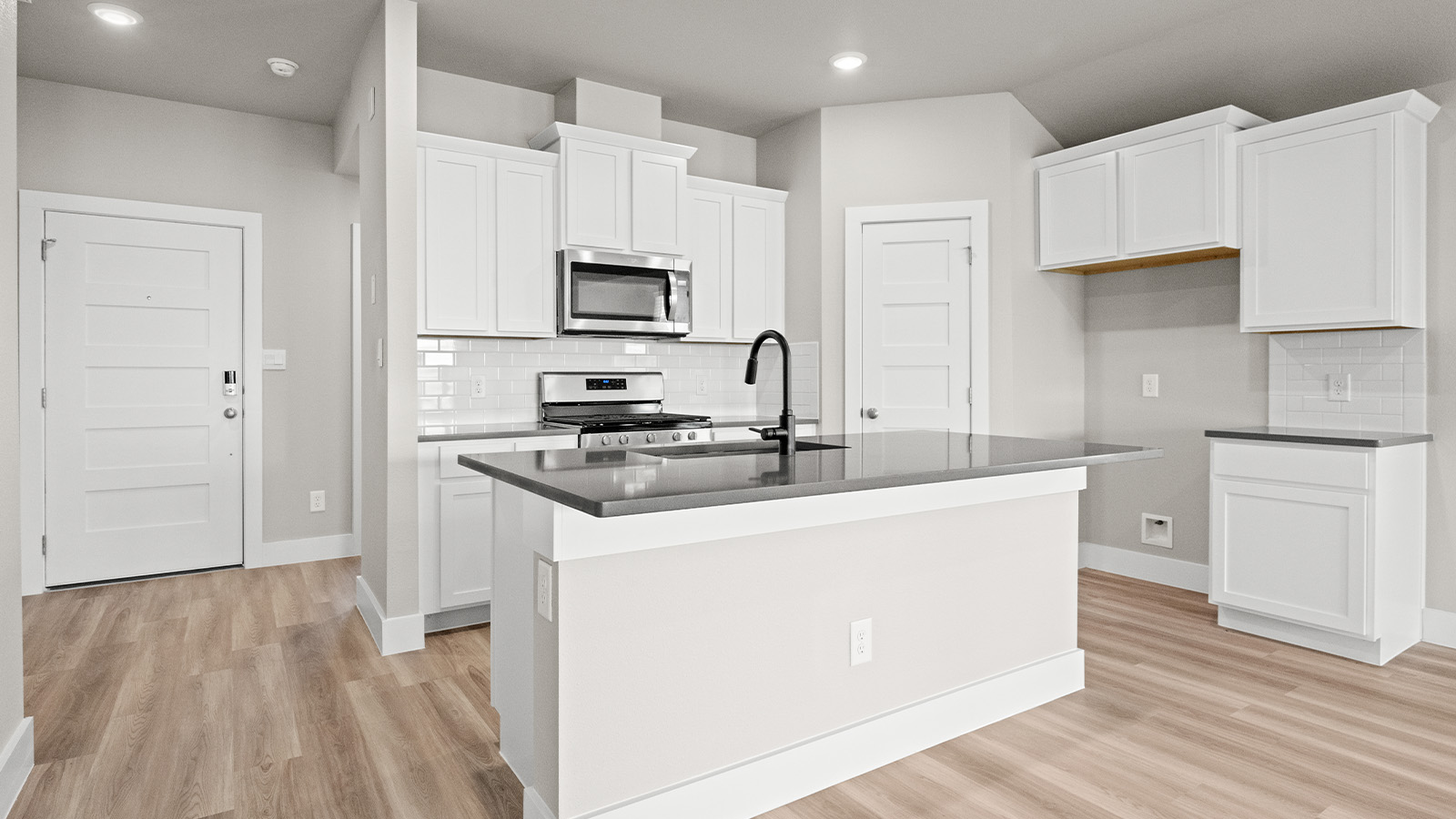Island kitchen with white shaker cabinet and dark quartz countertops