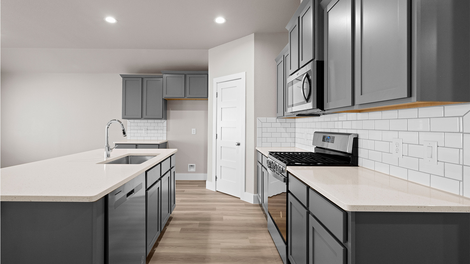 Kitchen with gray shaker cabinets quartz counters corner pantry and stainless steel appliances