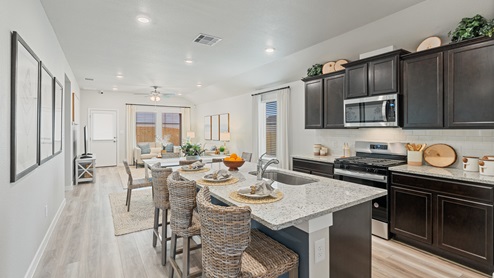 An open-concept kitchen, dining, and living room area with multiple large windows, a backdoor leading to the backyard and recessed lighting.