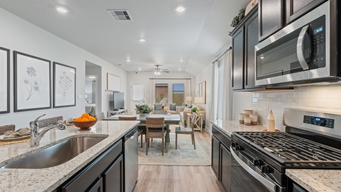 A view from the kitchen to the dining and living room, with many windows and visibility into the backyard.