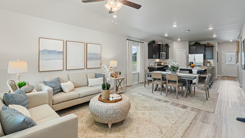 An open-concept kitchen, dining and living room area with wood-look flooring and calming, neutral decor.