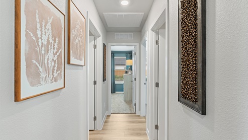 A hallway with wood-look flooring, bright walls and modern decor hung on the walls.