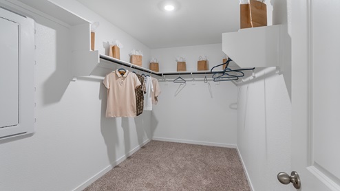 A spacious walk-in closet with neutral carpets, built-in clothes racks and shelving.