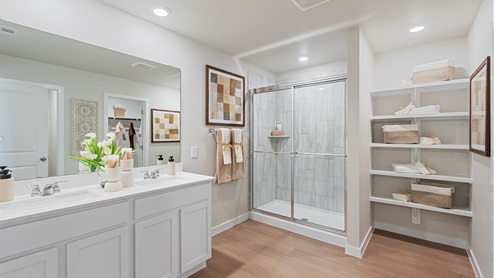 A modern bathroom featuring a double sink white vanity with white granite countertops and walk-in shower and with built in shelves.