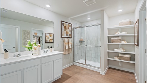 Primary bathroom featuring a double sink white vanity with white granite countertops and walk-in shower and with built in shelves.