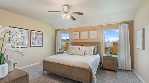Spacious primary bedroom with carpeted floors, two large windows, and trey ceilings.