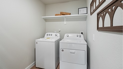 Spacious laundry area has room for a washer and dryer with built in shelves