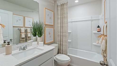 Bathroom with single sink white vanity and white granite tops with white tile shower and tub combo.