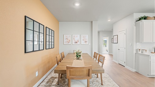 Side view of the dining area with kitchen to the right and foyer behind.