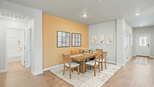 Orange accent wall dining area with the kitchen and living area adjacent.