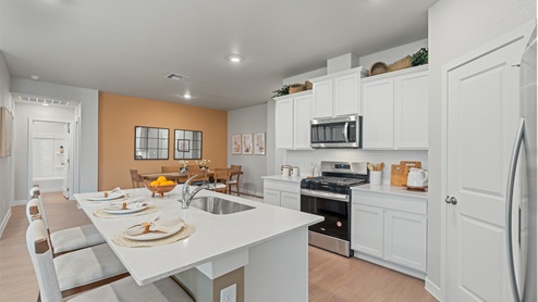 Spacious kitchen with dining area and hall leading to a bathroom and bedrooms.