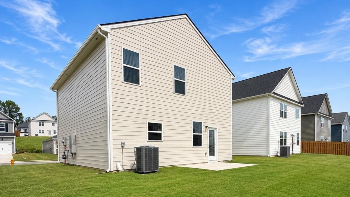 Rear of two story home with back patio and lush green lawn