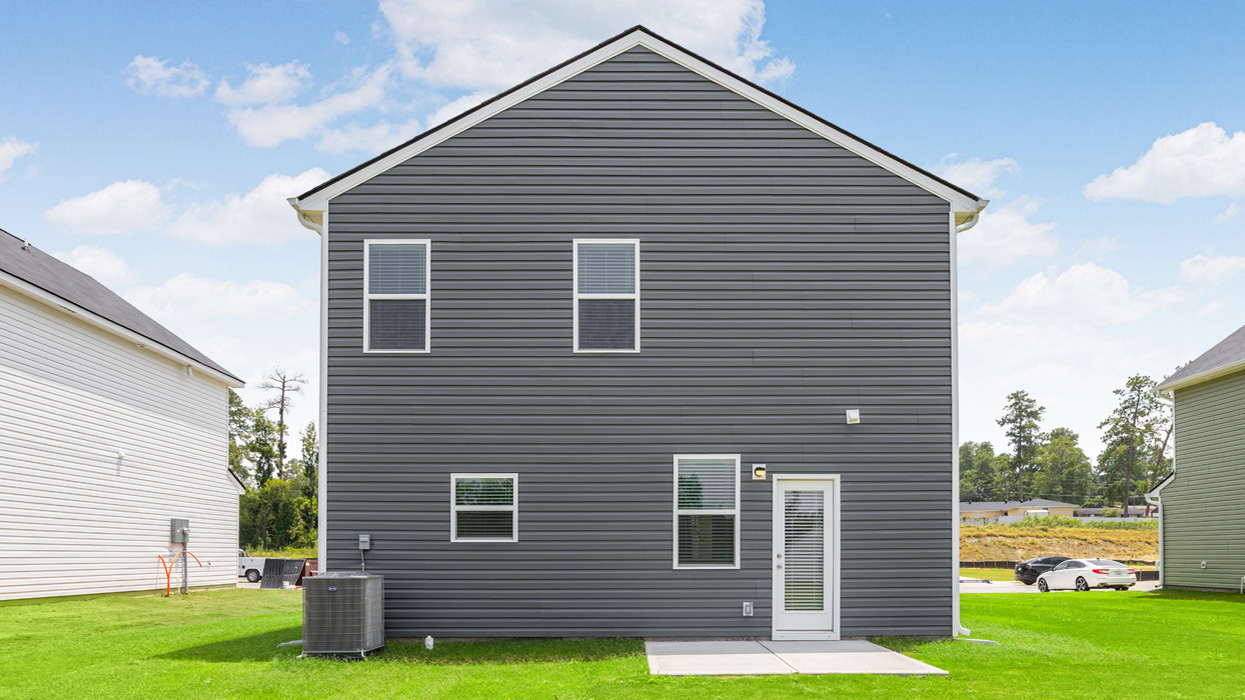 Two story blue home with back patio and lush green lawn