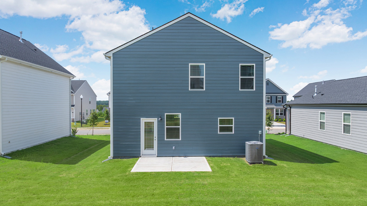 Two story blue home with back patio and lush green lawn