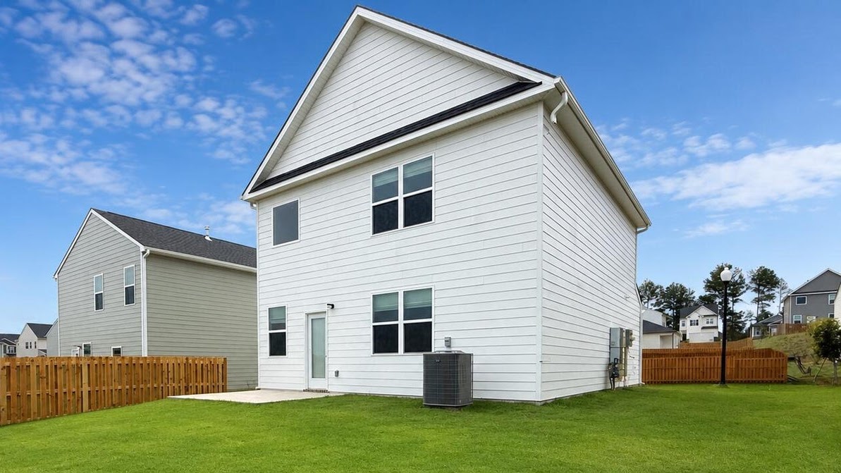 Rear of two-story white home with back patio.