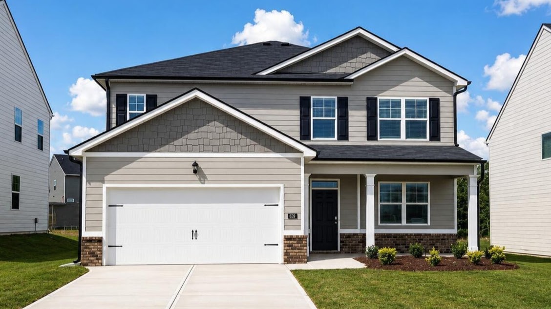 Two story tan home with covered porch and two car garage