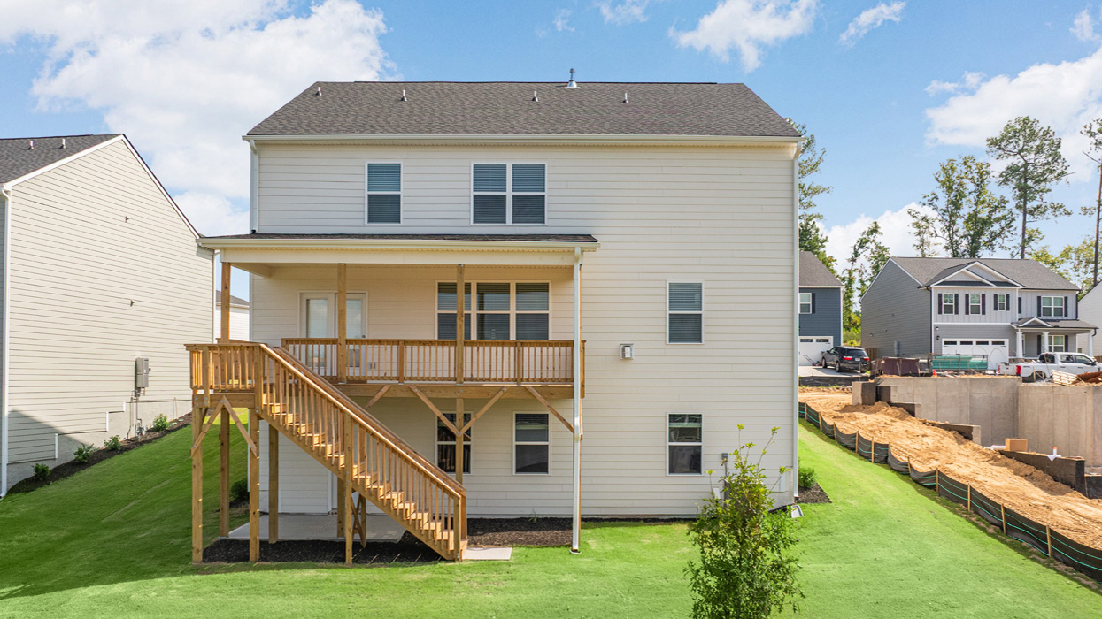Rear of two-story home with unfinished basement, extended covered back deck, and staircase leading to lower basement level