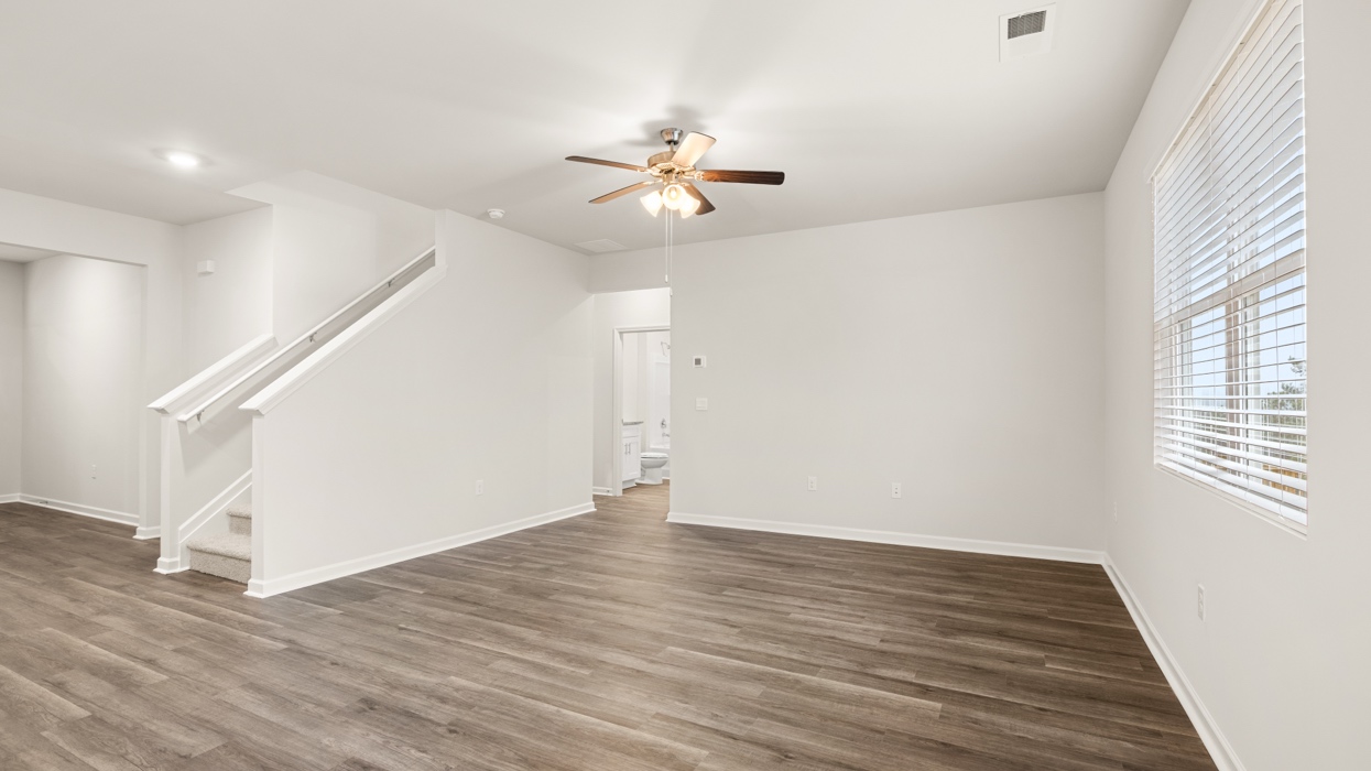 angled living room with natural light and ceiling fan