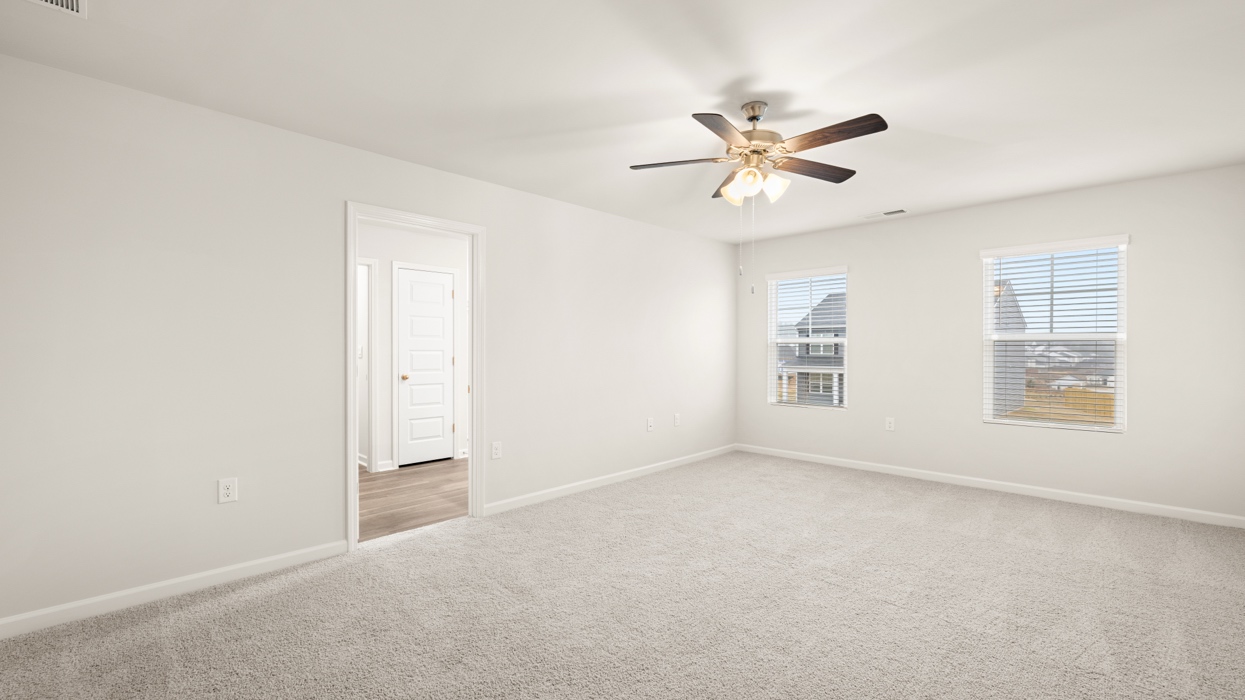 angled primary bedroom with natural light and ceiling fan