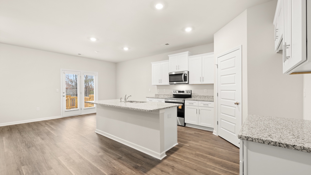 angled kitchen and dining room with large center island and spacious white cabinetry