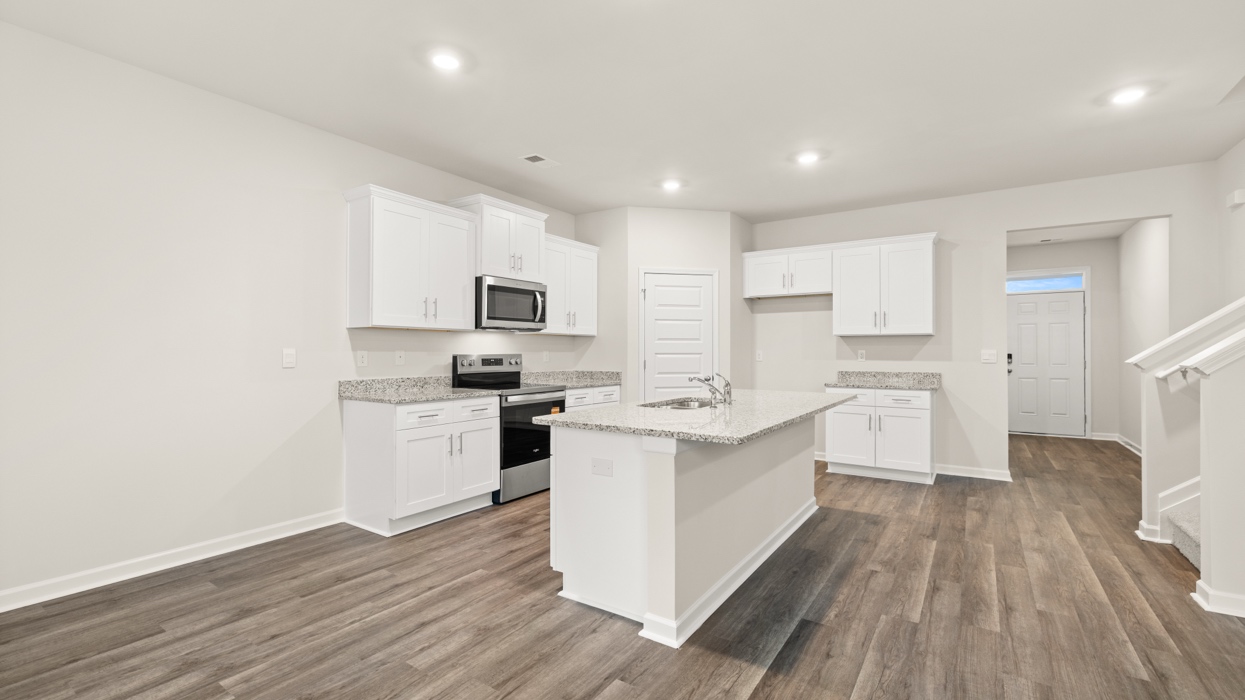 angled kitchen with large center island and spacious white cabinetry