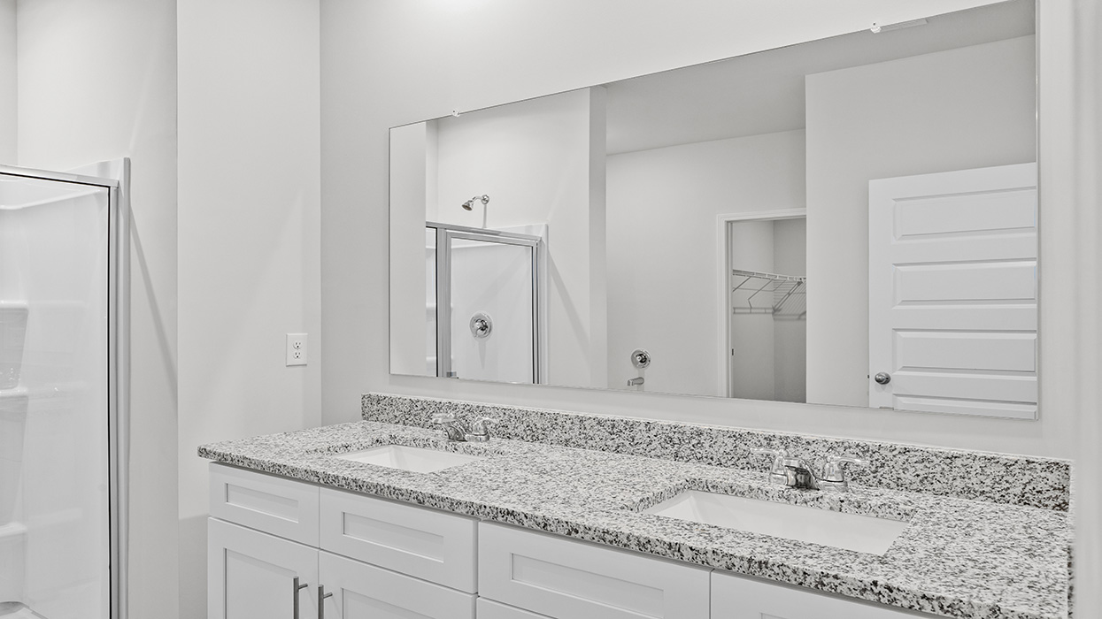 Primary bathroom with double vanity, shower with glass door, soaking tub, water closet, and expansive primary closet.