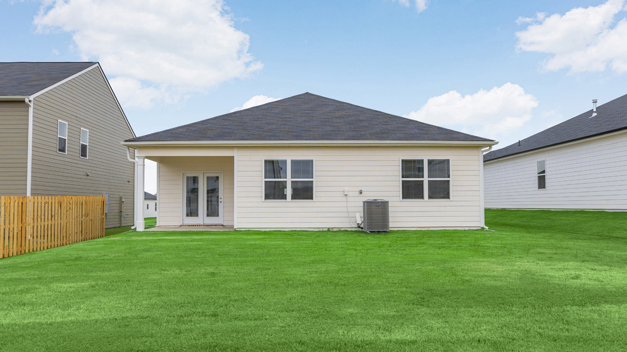 Rear of cream ranch home with covered porch and lush lawn