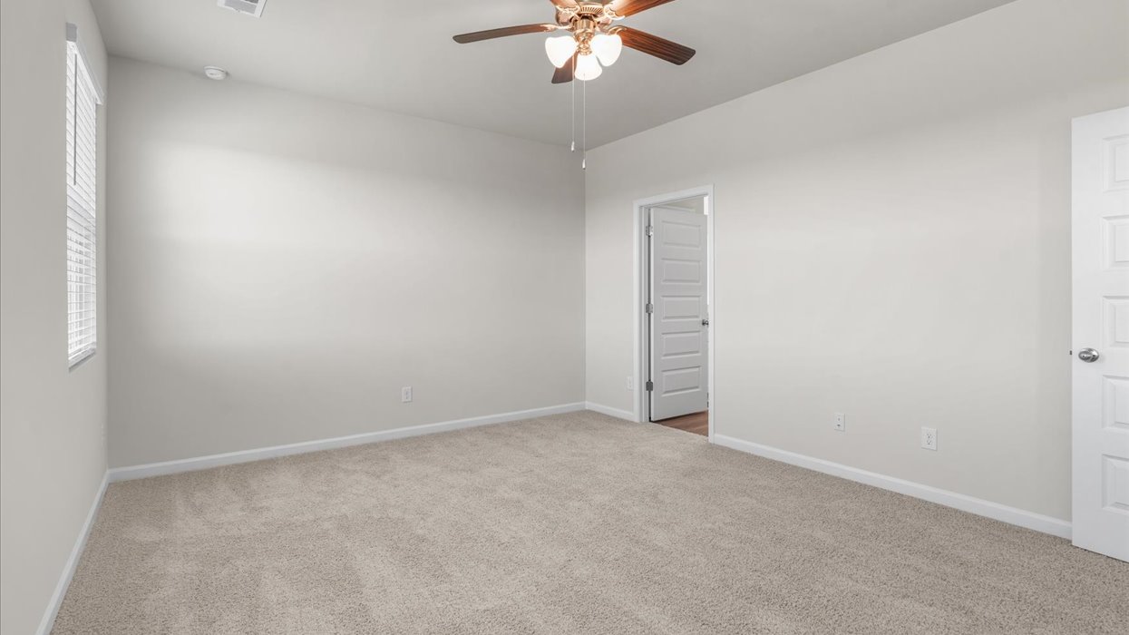 Primary bedroom with ceiling fan and carpeting.