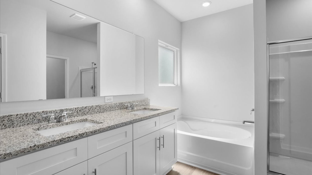 Primary bathroom with double vanity, soaking tub, and shower with glass door.