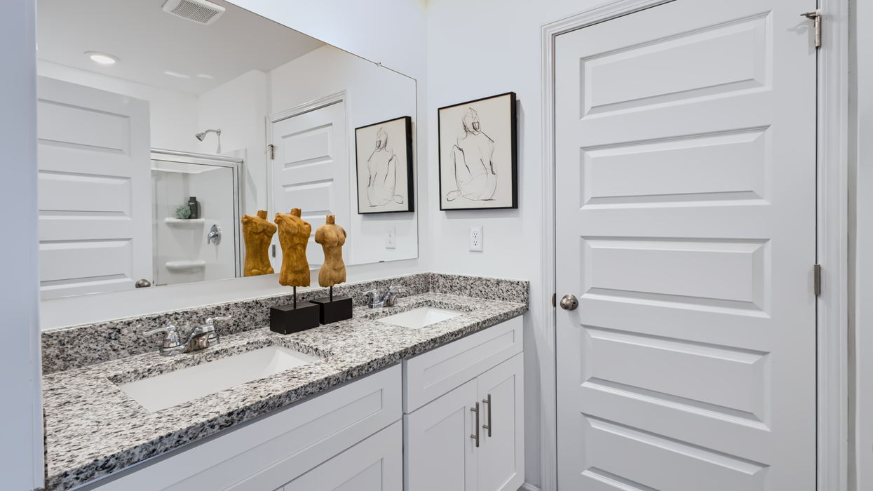 Primary bath with double vanity and views of water closet with commode.