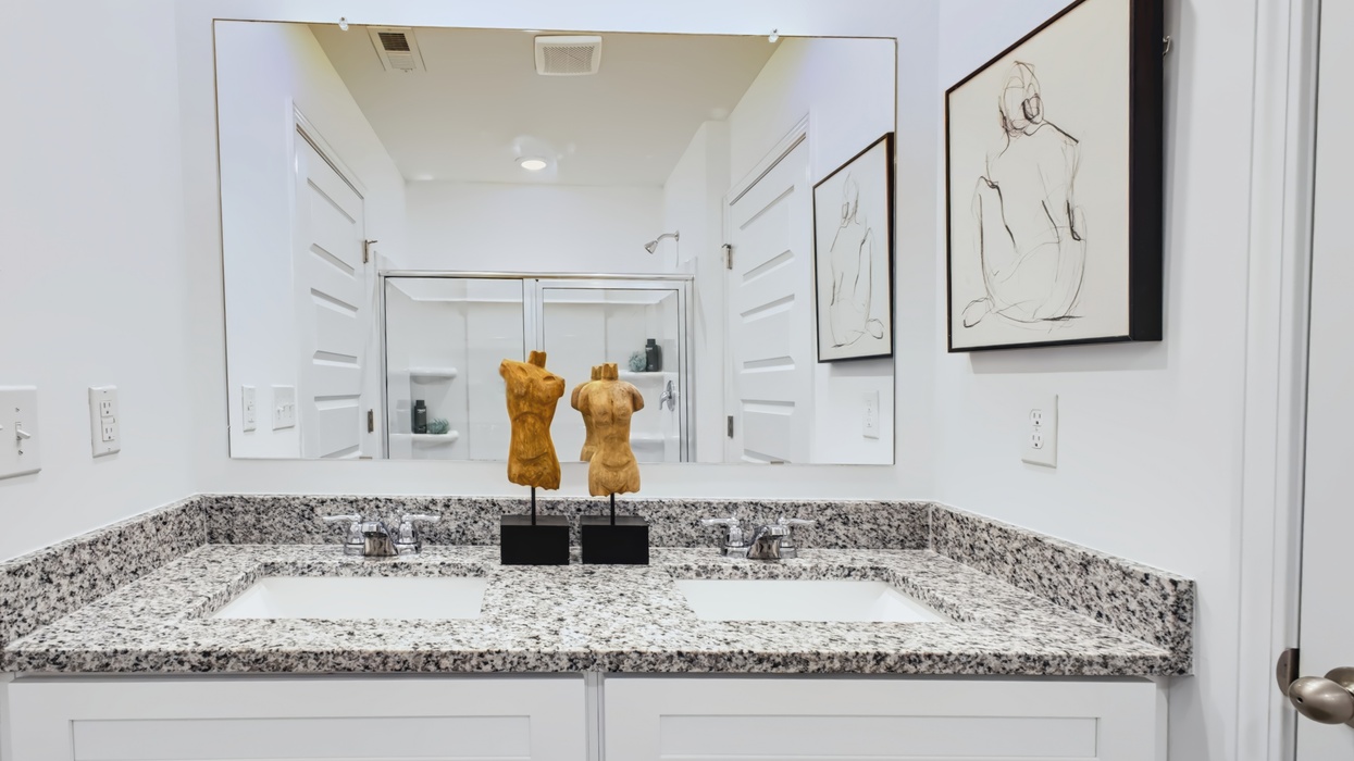 Primary bath with double vanity and views of water closet with commode.