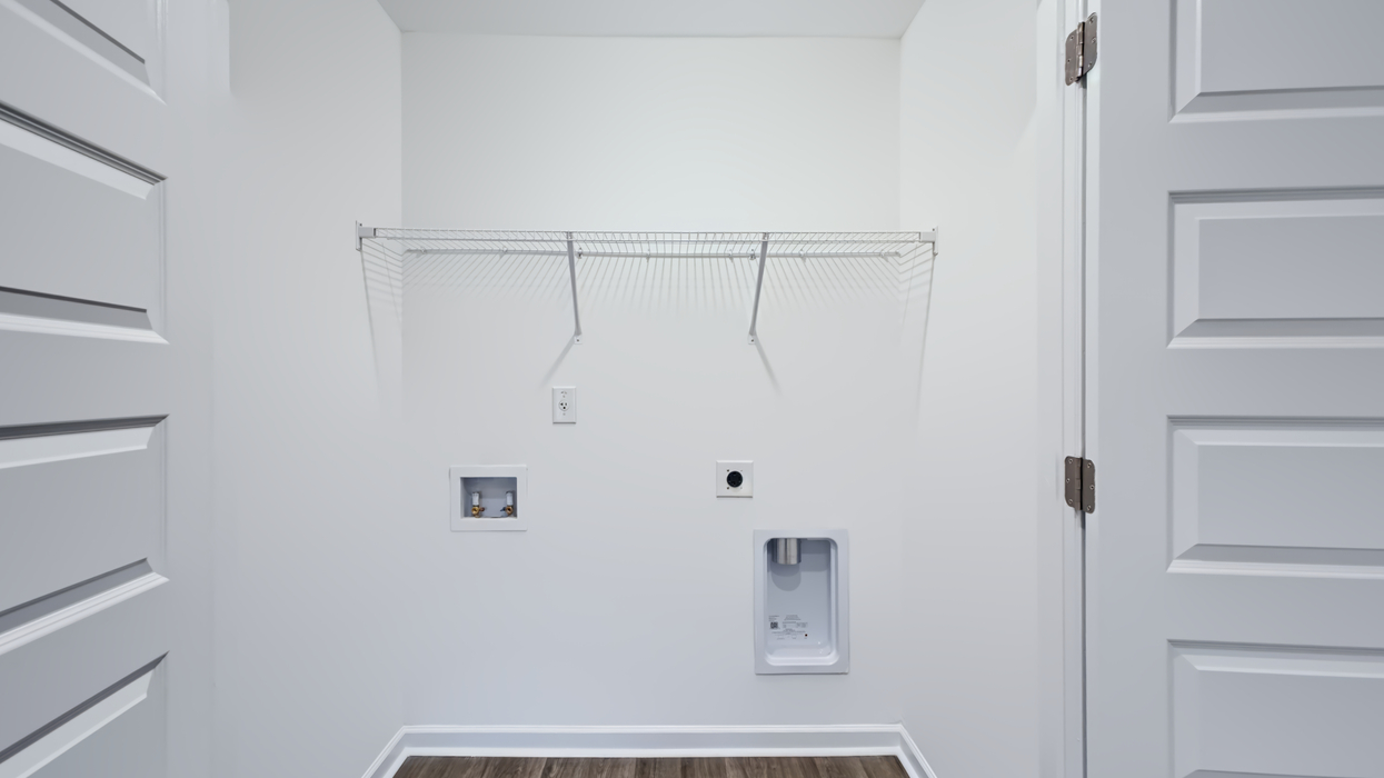 Laundry room upstairs with washer and dryer hookups and shelving above.