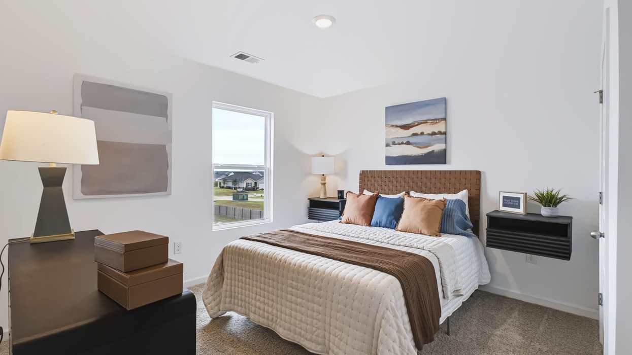 Carpeted guest bedroom with flush mount light fixture.