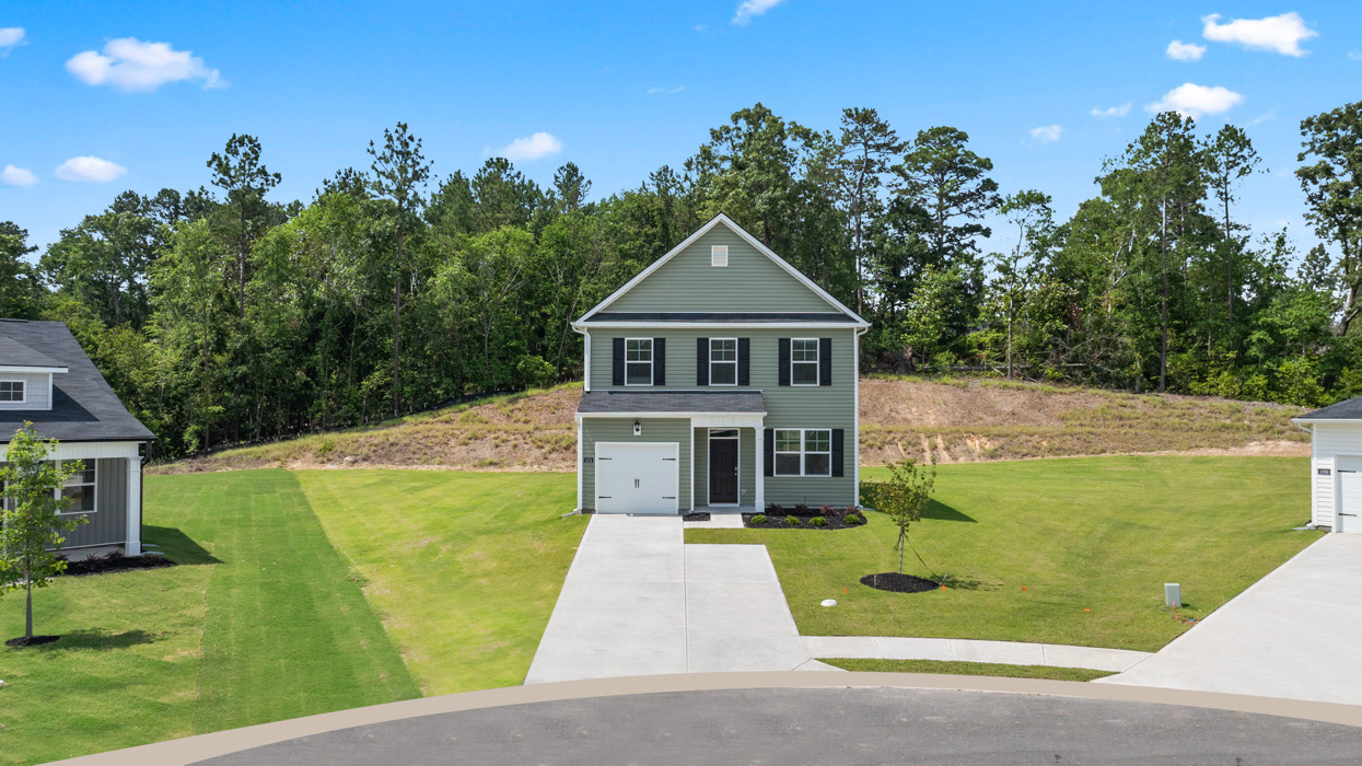 sage green home with two car garage