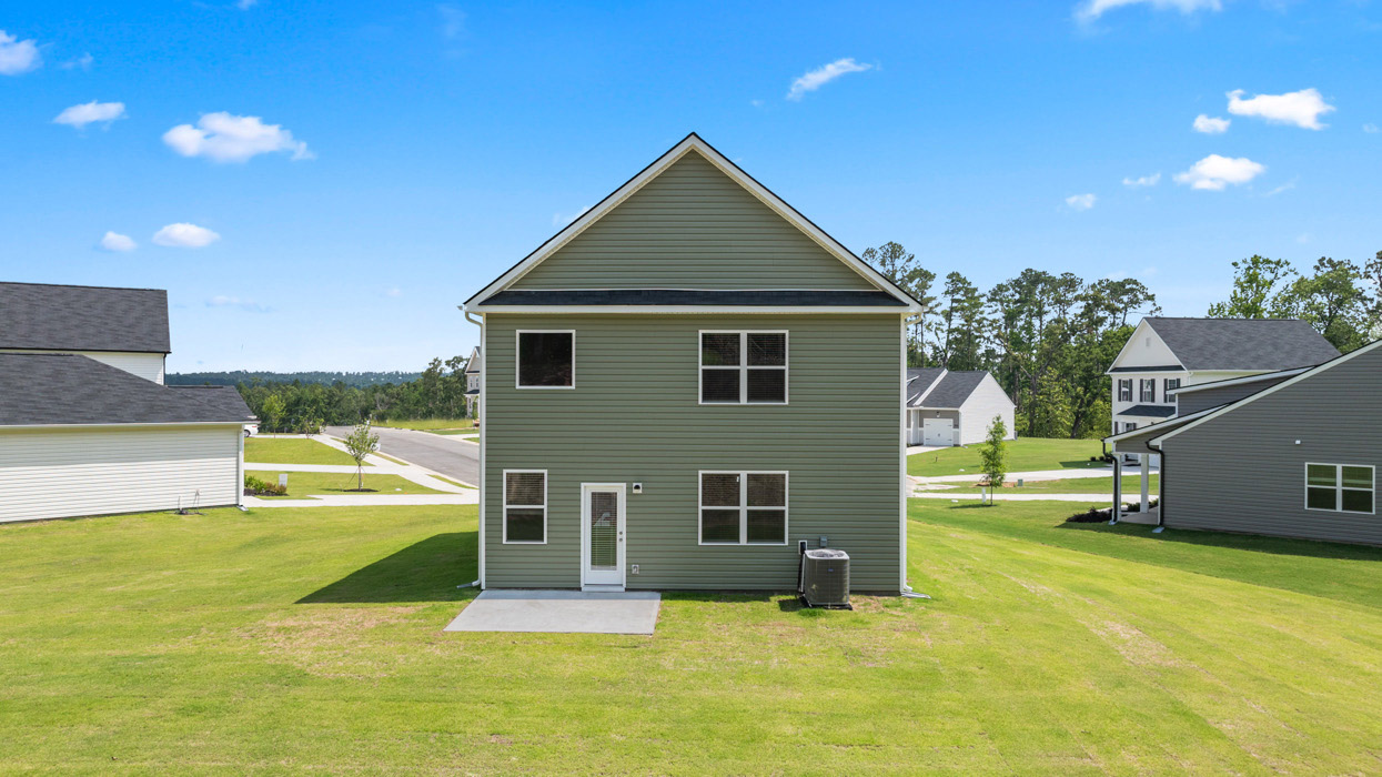 Rear of sage green home with two car garage
