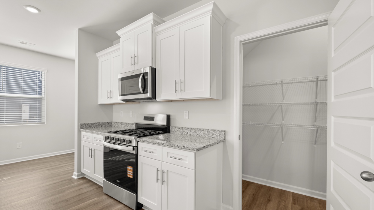 Bright modern kitchen with granite counters, stainless steel appliances, and large center island opening to living and dining space.