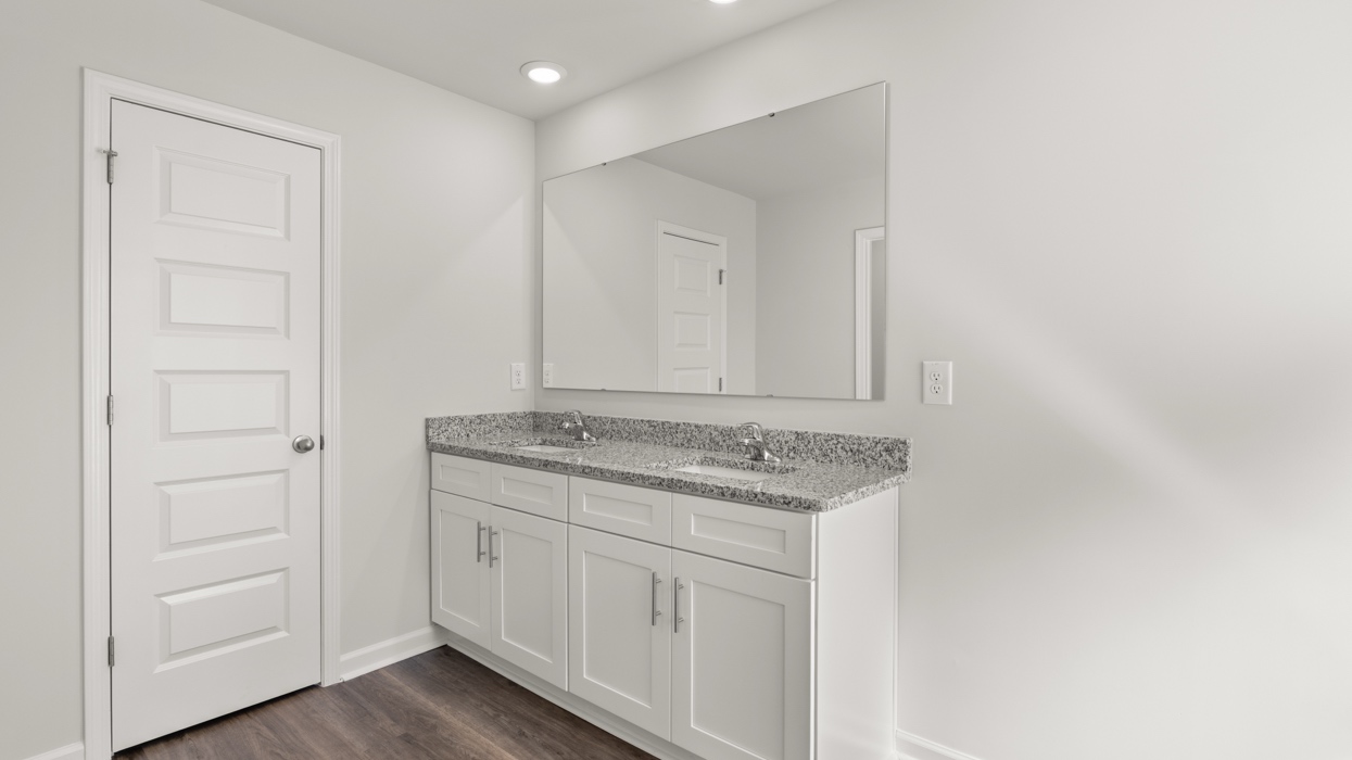 Primary bath with double vanity, garden tub, shower with glass door, linen closet, and water closet with commode.