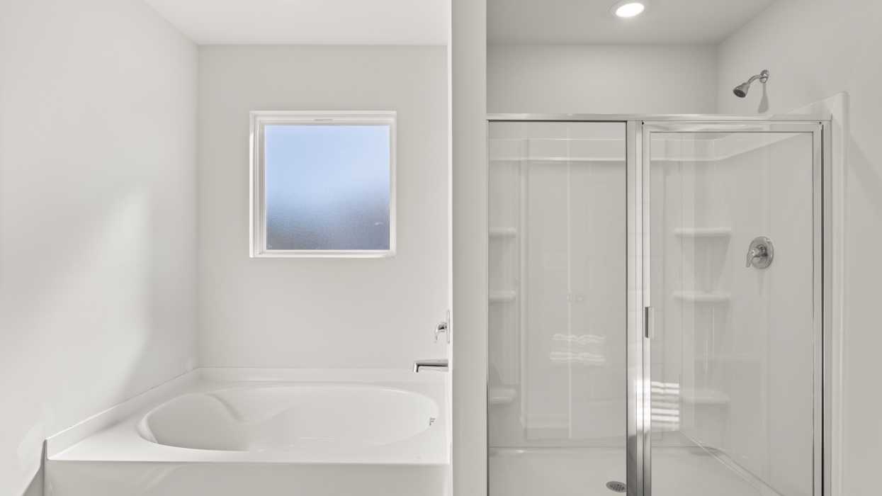 Primary bath with double vanity, garden tub, shower with glass door, linen closet, and water closet with commode.