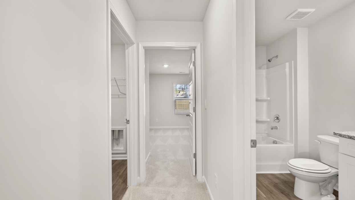 Hallway upstairs with sightlines to guest bath, guest bedroom, and laundry.