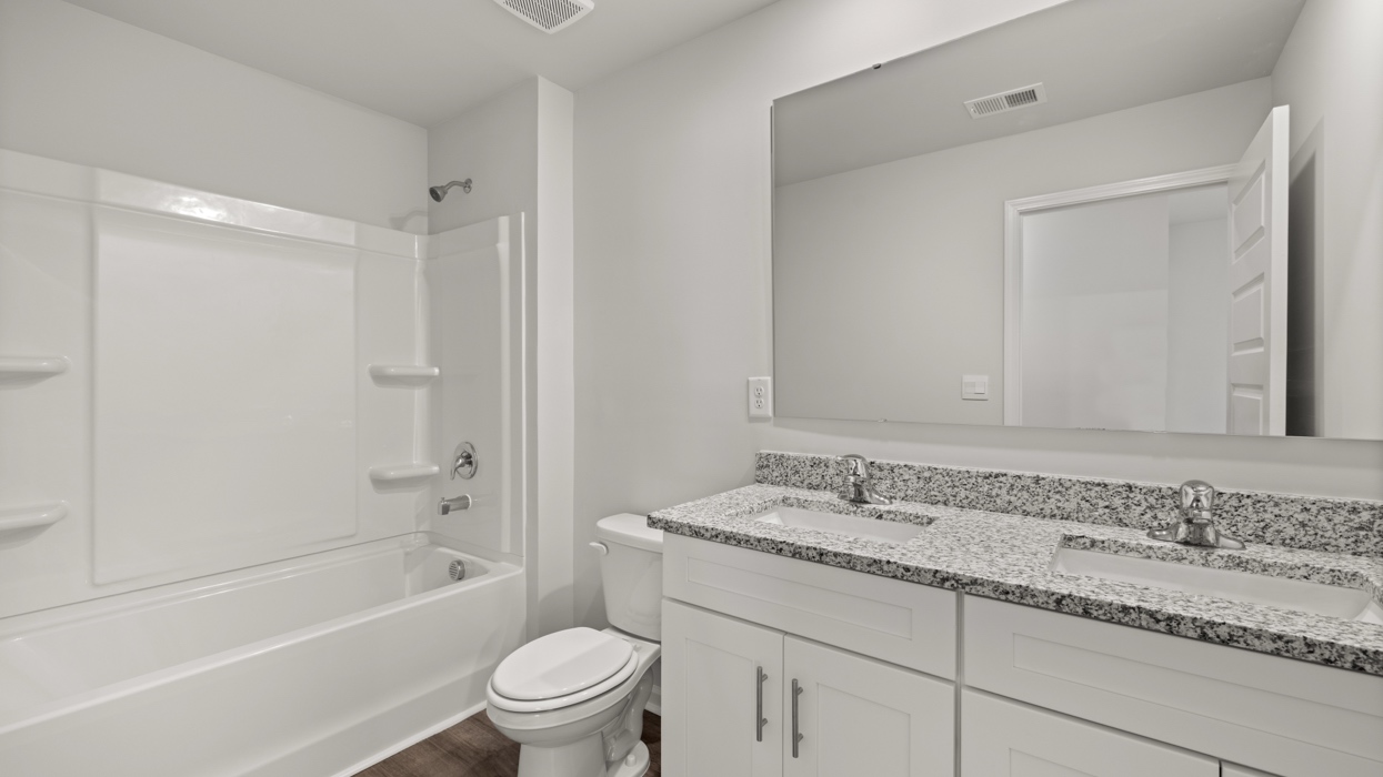 Guest bath upstairs with double vanity, commode, and shower/tub combo.