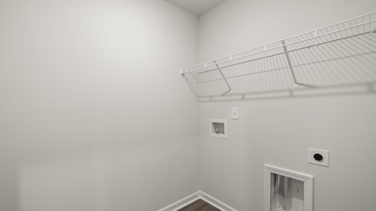 Upstairs laundry room with appliance connections and shelving.