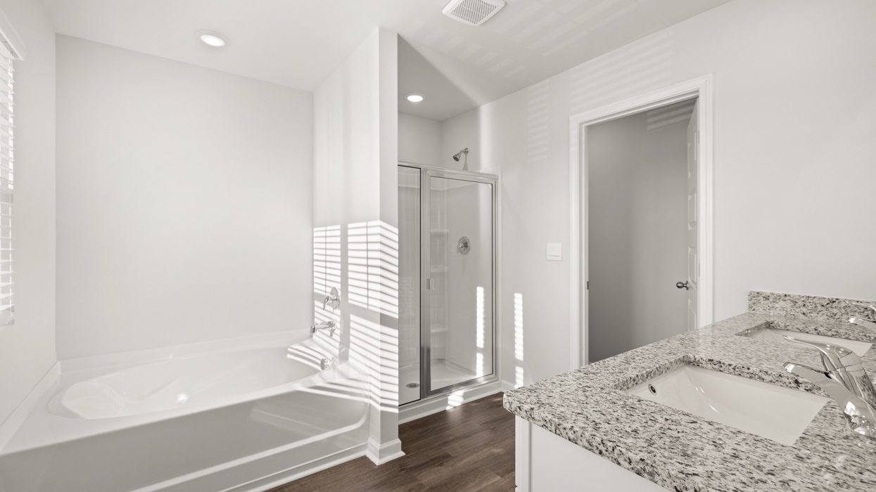 Primary bath with double vanity, shower with glass door, garden tub, water closet with commode, and primary closet.