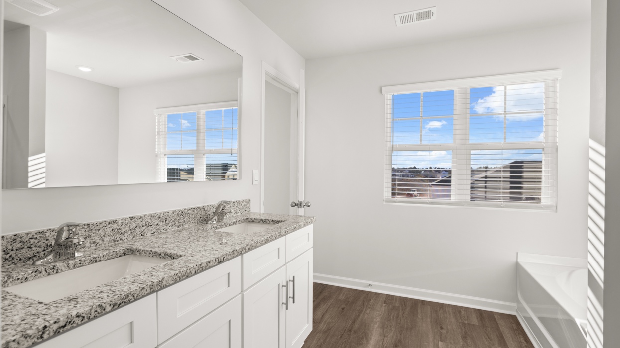 Primary bath with double vanity, shower with glass door, garden tub, water closet with commode, and primary closet.