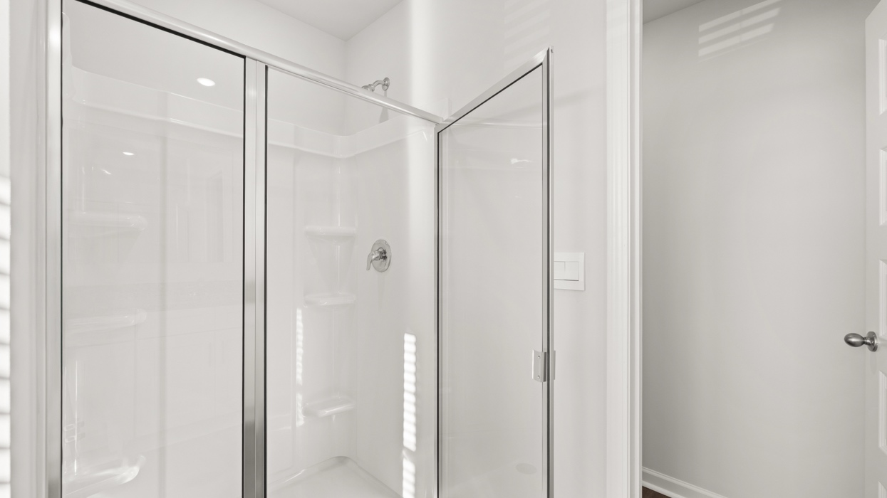 Primary bath with double vanity, shower with glass door, garden tub, water closet with commode, and primary closet.
